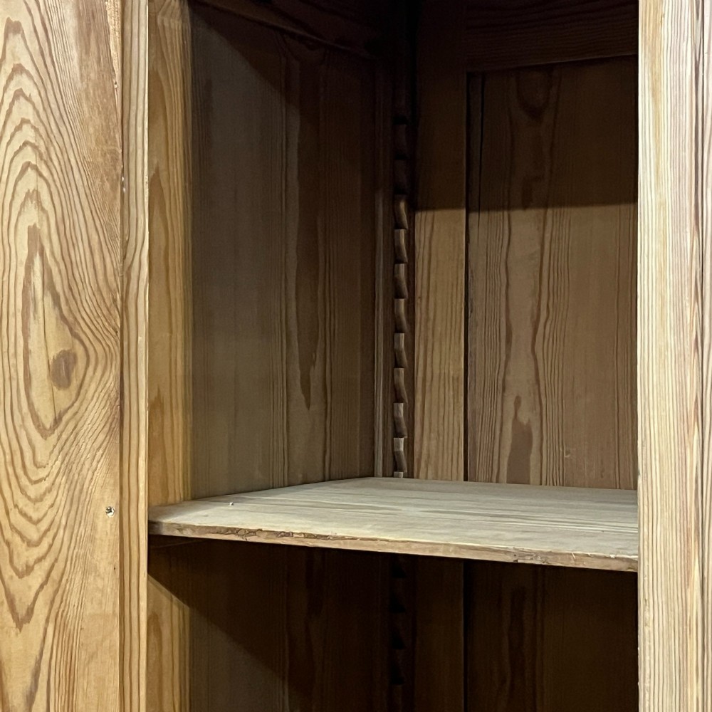 A freestanding 1930s pine compactum wardrobe featuring a upper mirror above four drawers on the left and a tall panelled door on the right. View X