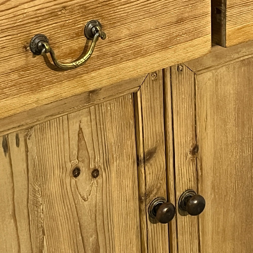 A small antique pine kitchen dresser featuring an upper rack with arched open shelves and a single cupboard door above a base unit with two drawers and two panelled doors. View VII