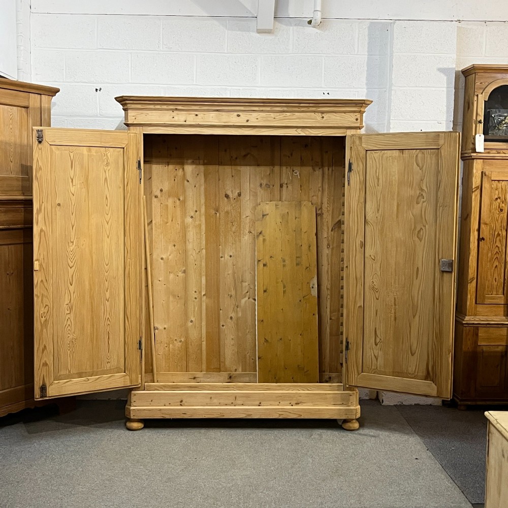 A large French pine double wardrobe featuring twin panelled doors, iron escutcheons, a moulded cornice, and rounded feet. View II