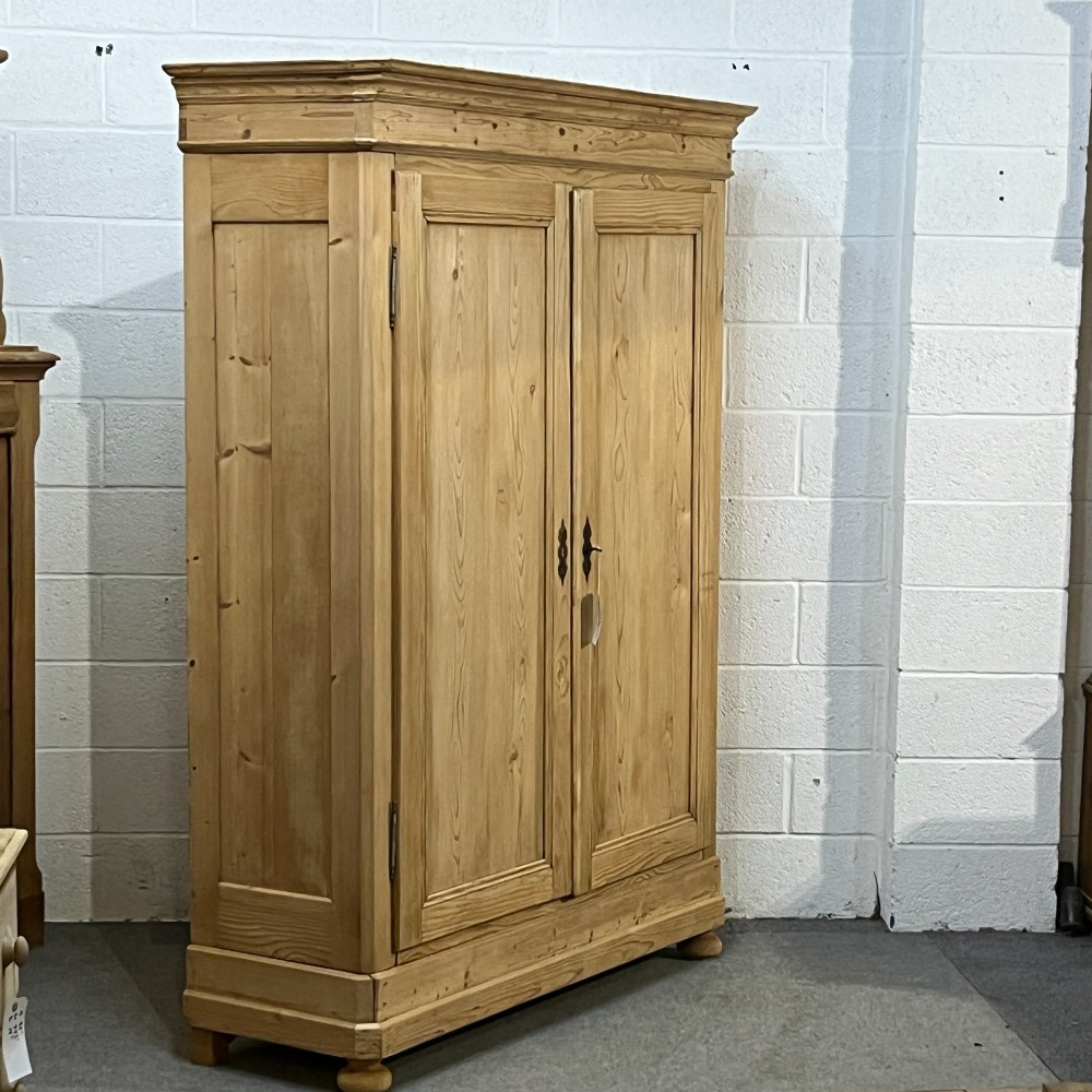 A large French pine double wardrobe featuring twin panelled doors, iron escutcheons, a moulded cornice, and rounded feet. View IV