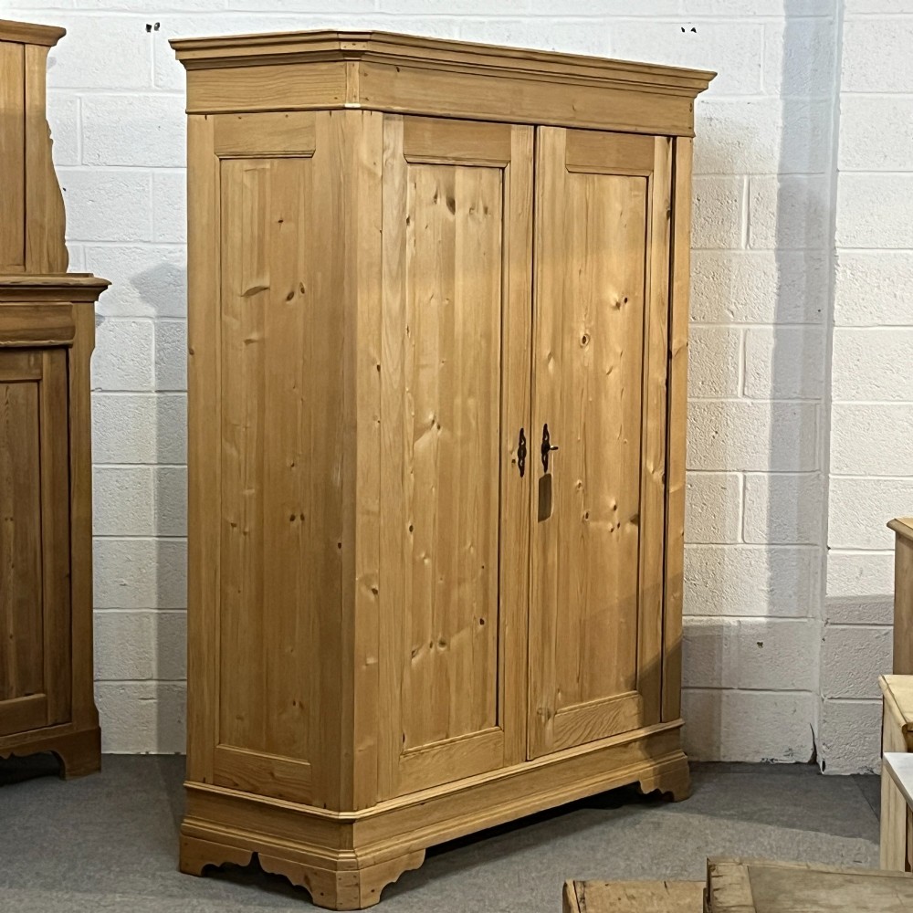 A large two-door antique pine wardrobe with fielded panels, a plain stepped cornice, moulding at the base, and central iron escutcheons. View IV