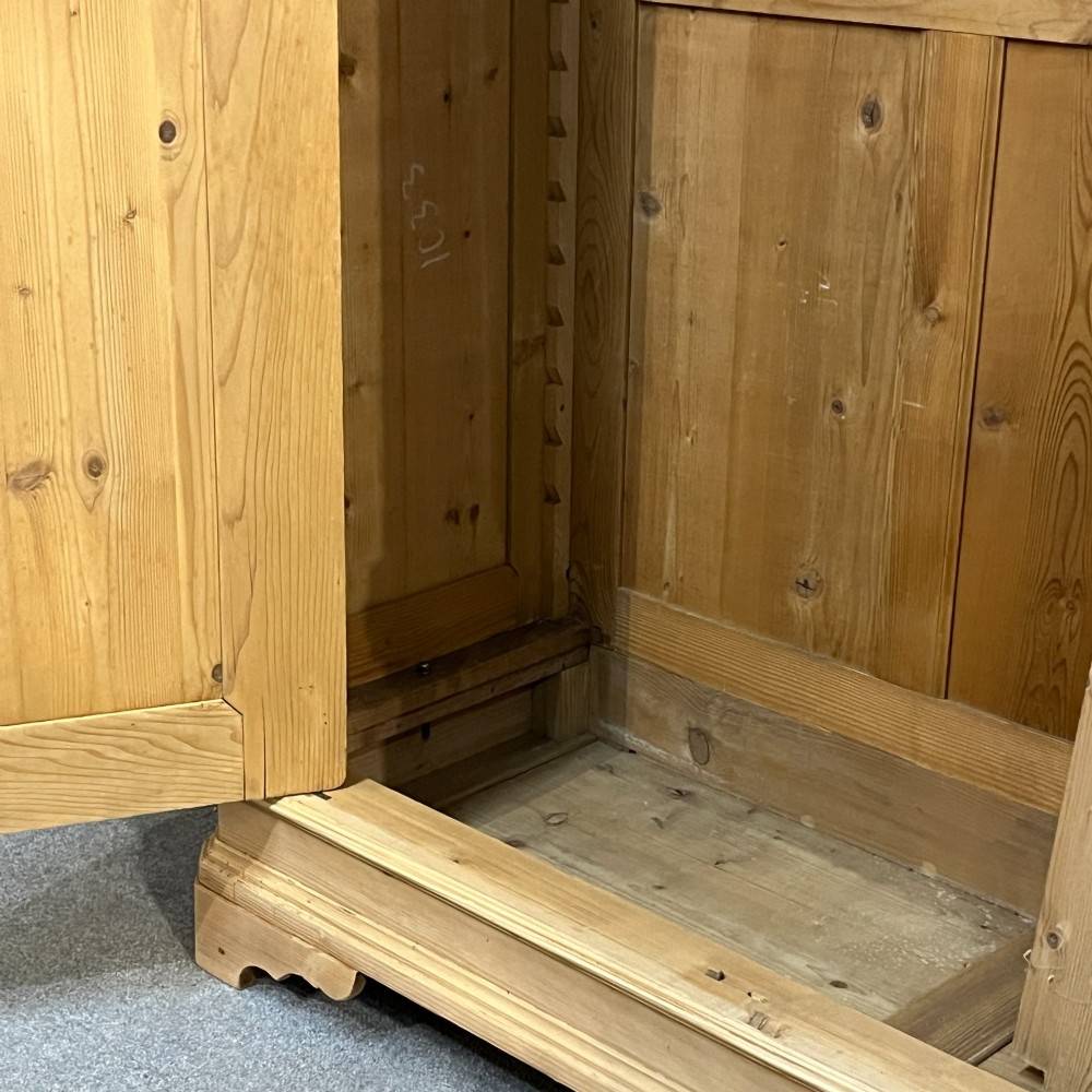 A large two-door antique pine wardrobe with fielded panels, a plain stepped cornice, moulding at the base, and central iron escutcheons. View VII