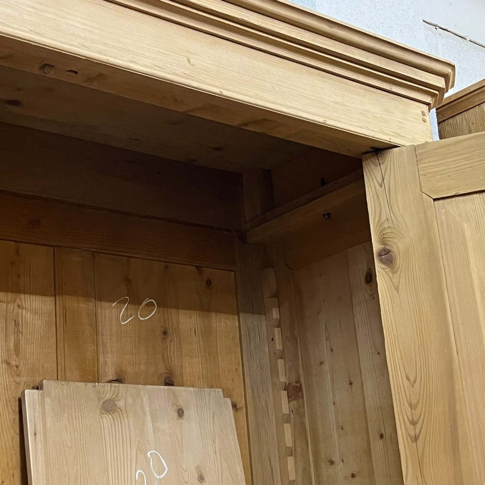 A large two-door antique pine wardrobe with fielded panels, a plain stepped cornice, moulding at the base, and central iron escutcheons. View VIII
