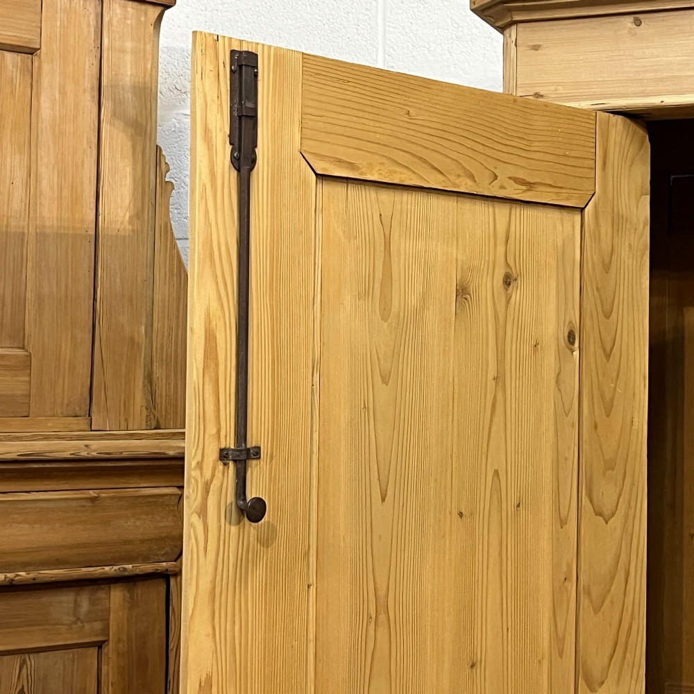 A large two-door antique pine wardrobe with fielded panels, a plain stepped cornice, moulding at the base, and central iron escutcheons. View IX