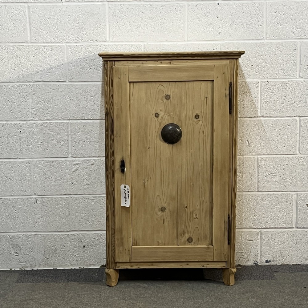 An antique single door pine larder cupboard featuring a central circular metal vent and dark iron hinges.