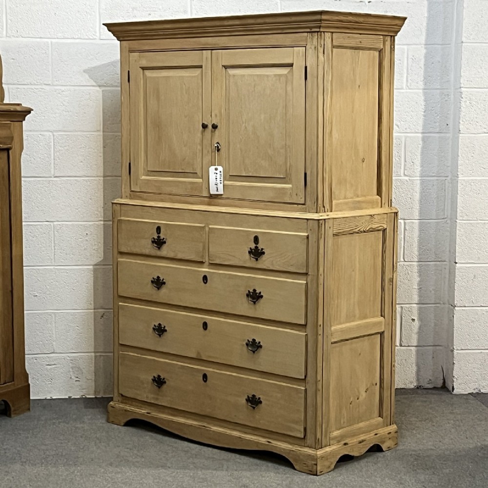 A nineteenth-century pale pine linen press featuring a double-door top cupboard set above two short and three long graduated drawers with brass handles. View II