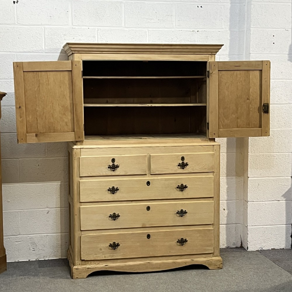 A nineteenth-century pale pine linen press featuring a double-door top cupboard set above two short and three long graduated drawers with brass handles. View V