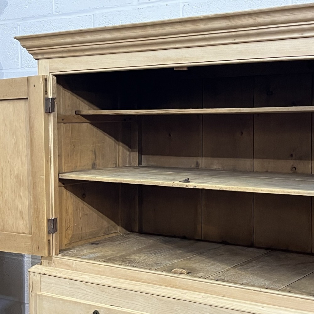 A nineteenth-century pale pine linen press featuring a double-door top cupboard set above two short and three long graduated drawers with brass handles. View VI