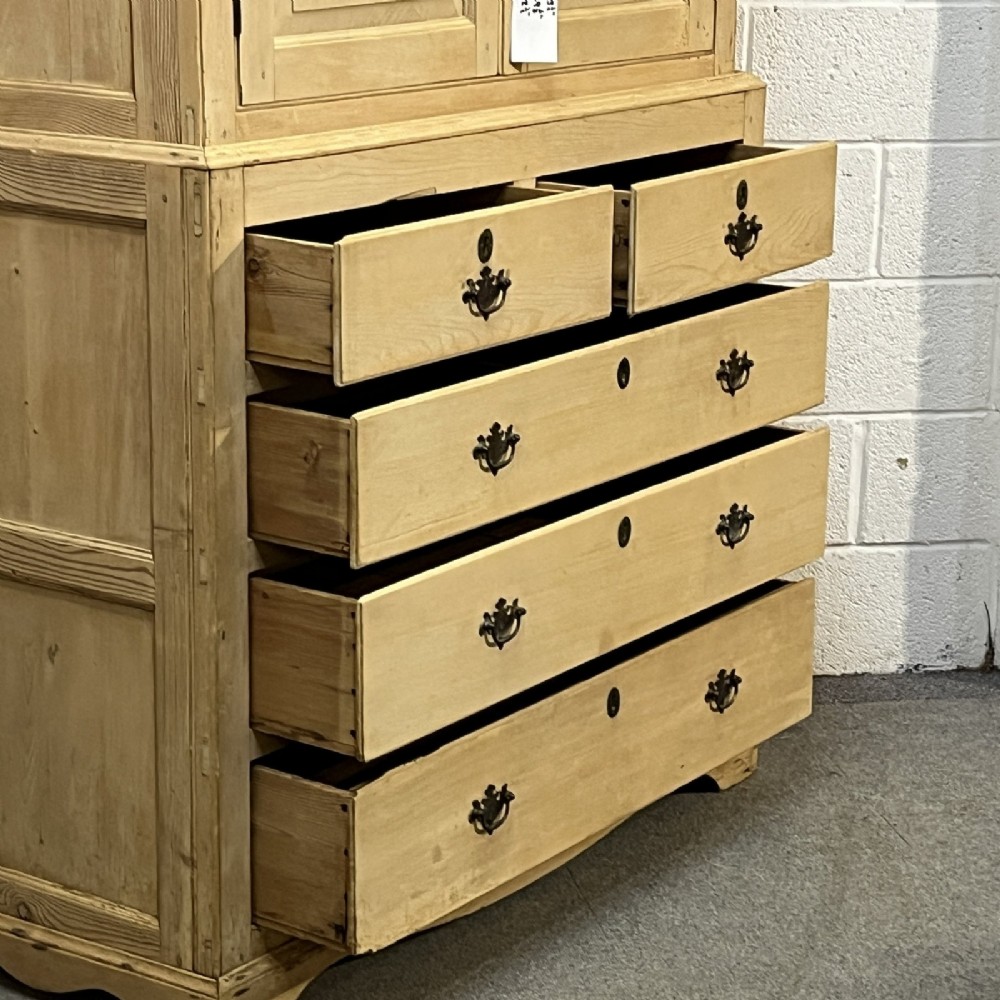 A nineteenth-century pale pine linen press featuring a double-door top cupboard set above two short and three long graduated drawers with brass handles. View VII