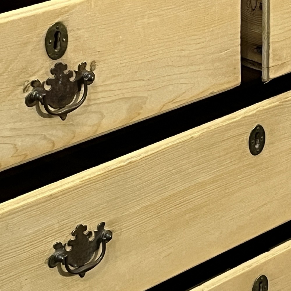 A nineteenth-century pale pine linen press featuring a double-door top cupboard set above two short and three long graduated drawers with brass handles. View VIII