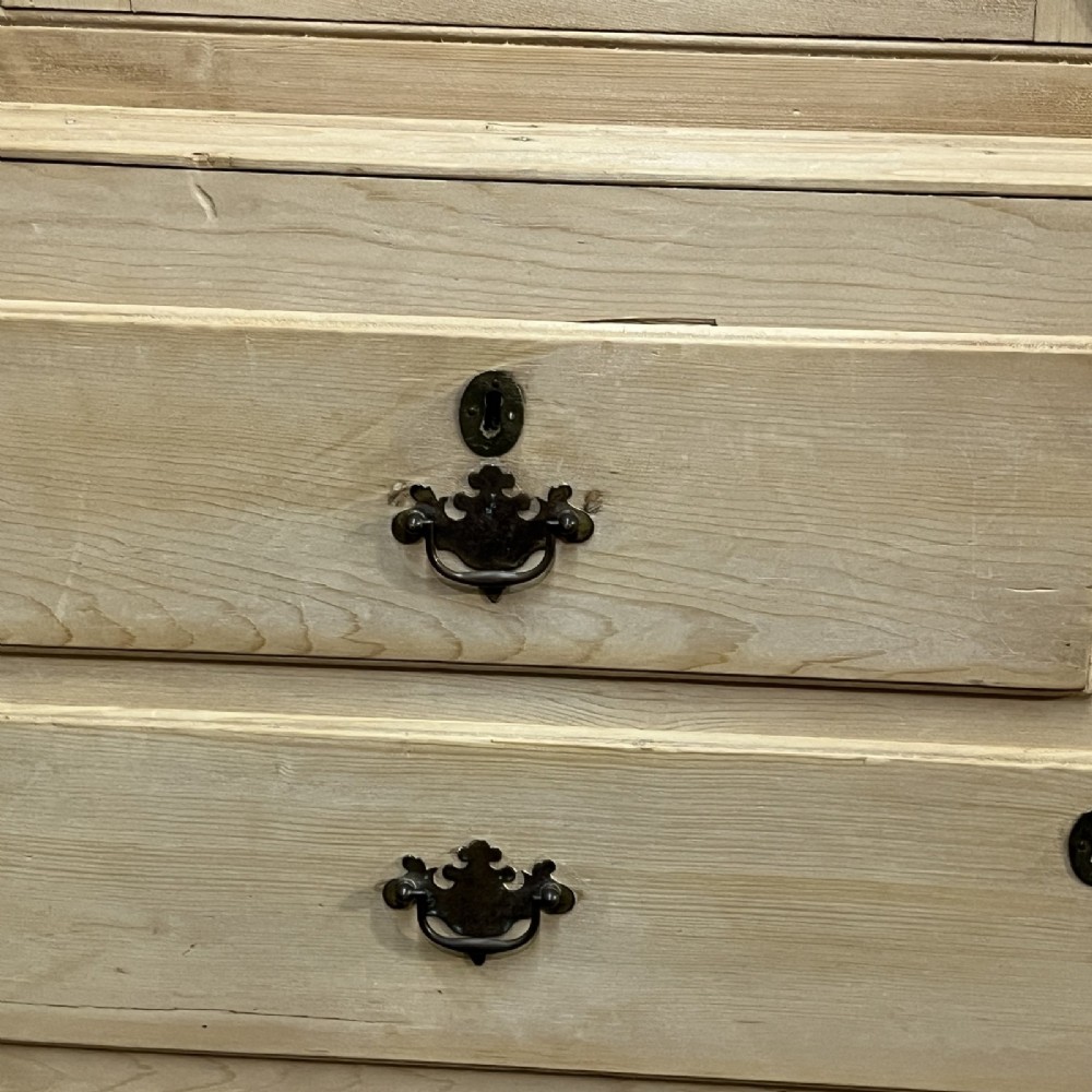 A nineteenth-century pale pine linen press featuring a double-door top cupboard set above two short and three long graduated drawers with brass handles. View IX