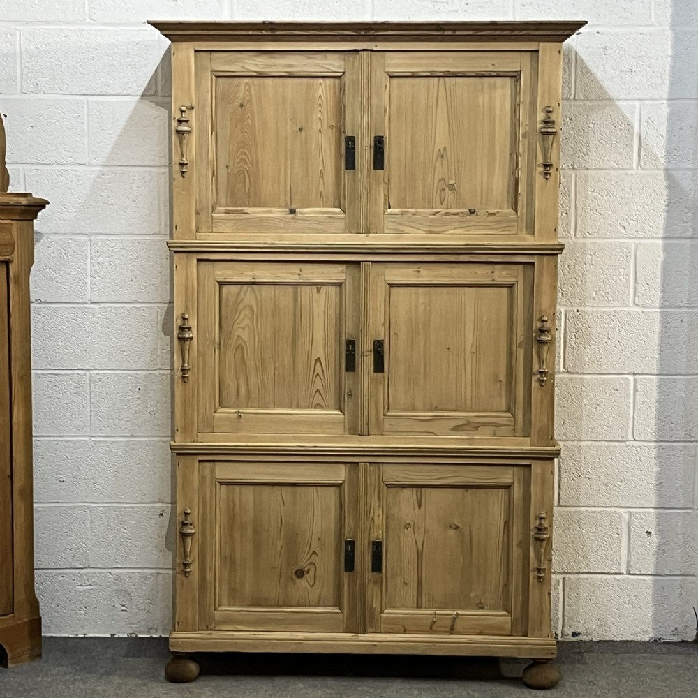 A three-section antique pine campaign cupboard featuring panelled doors, iron carrying handles on the sides, and rounded bun feet. View II