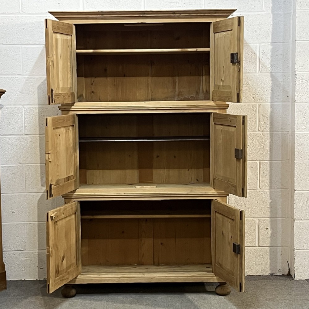 A three-section antique pine campaign cupboard featuring panelled doors, iron carrying handles on the sides, and rounded bun feet. View III