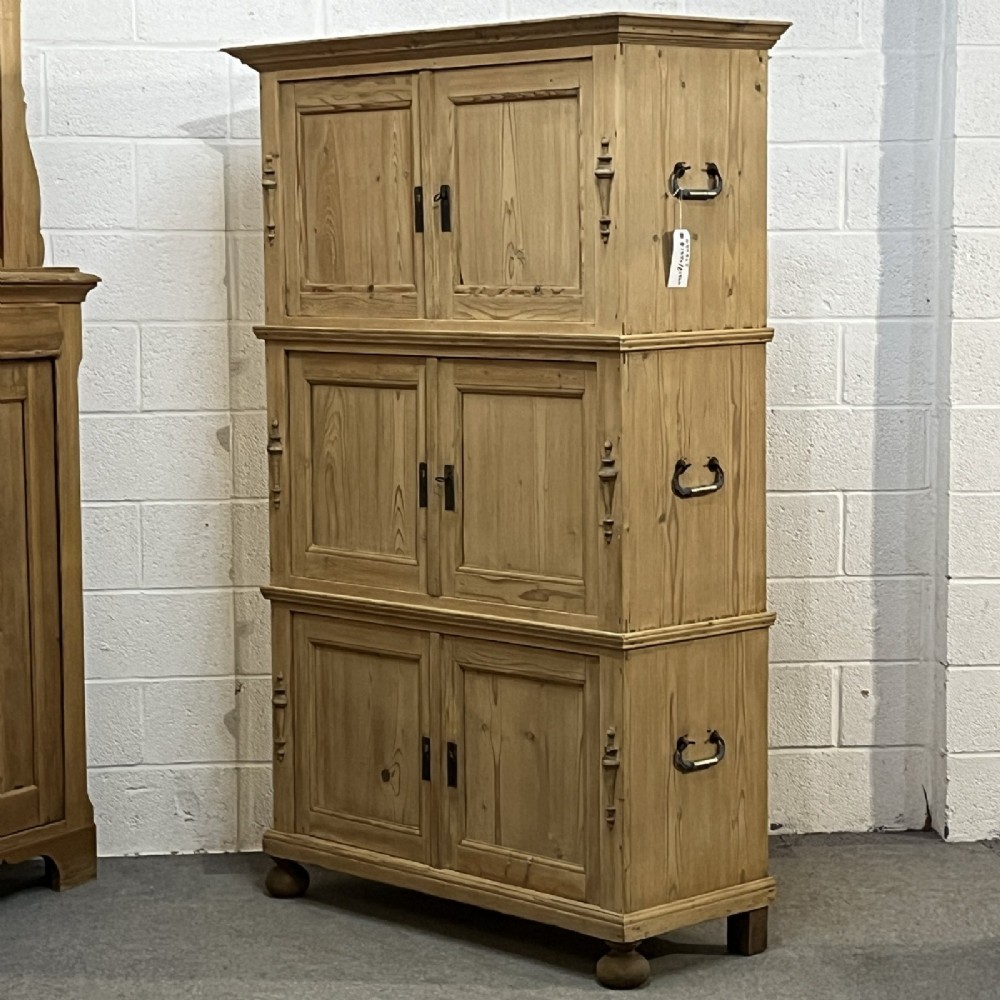 A three-section antique pine campaign cupboard featuring panelled doors, iron carrying handles on the sides, and rounded bun feet. View V