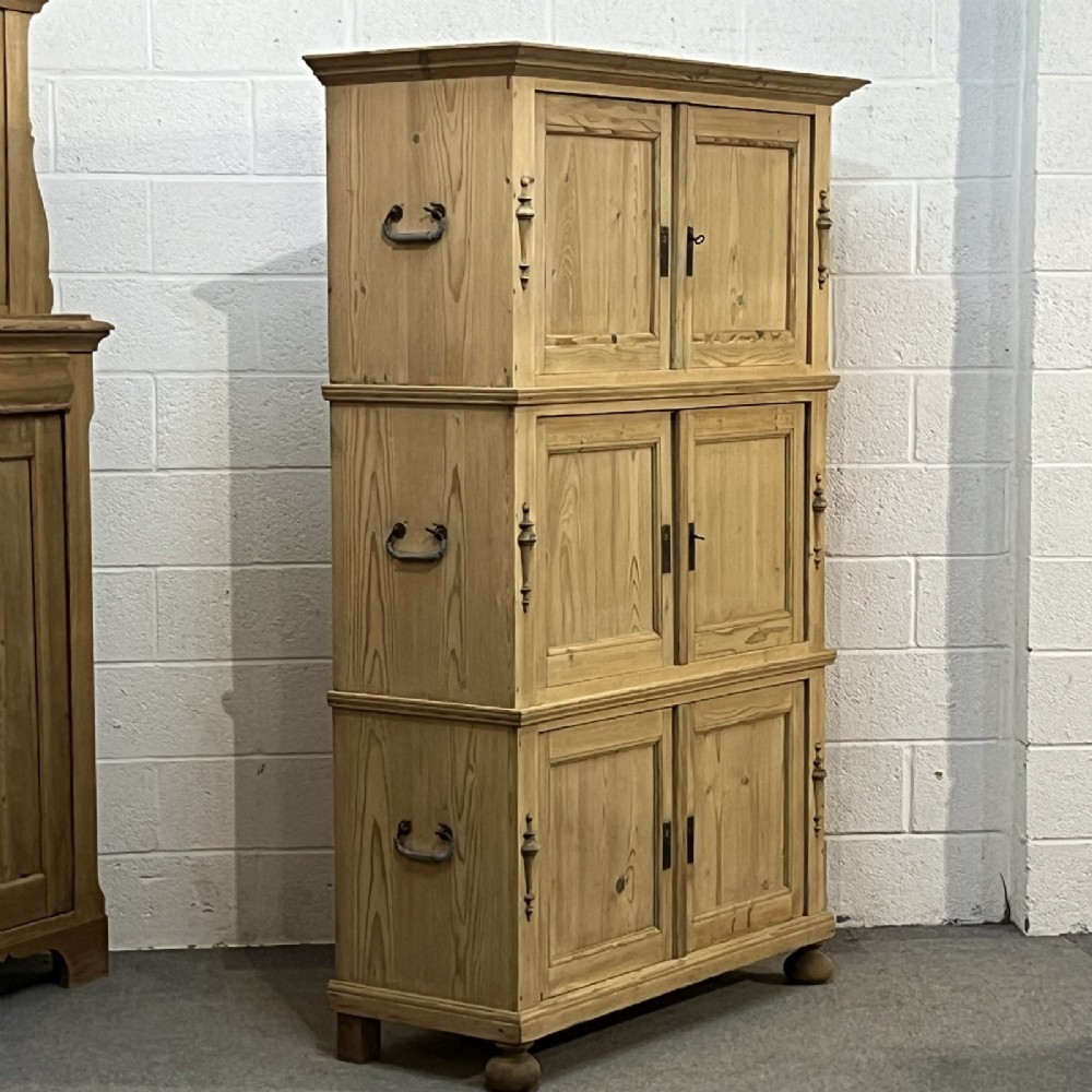 A three-section antique pine campaign cupboard featuring panelled doors, iron carrying handles on the sides, and rounded bun feet. View VI