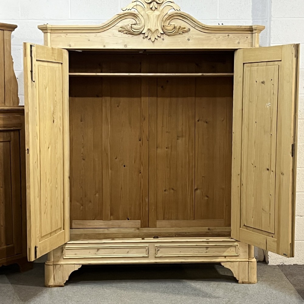 A large late nineteenth-century natural pine double wardrobe featuring a carved scroll pediment, arched door mouldings, and a flat plinth base. View IV