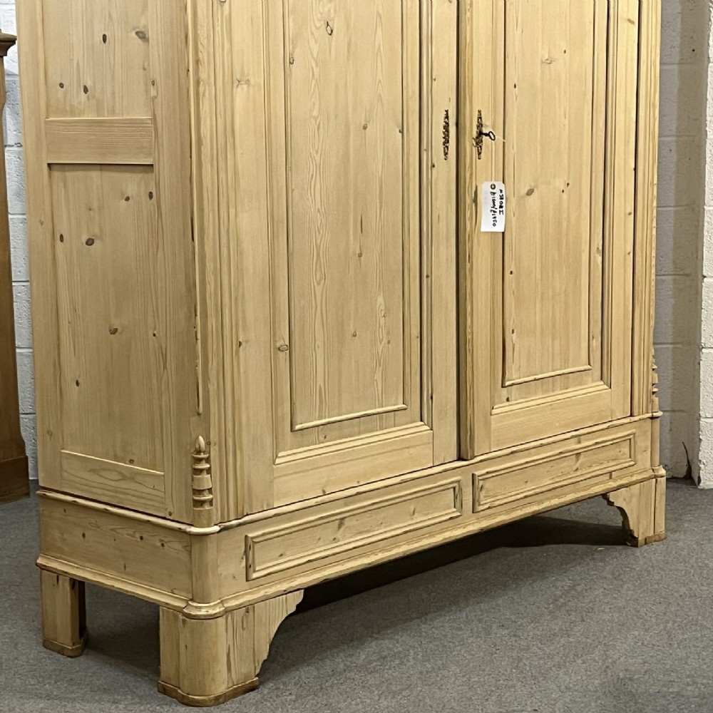 A large late nineteenth-century natural pine double wardrobe featuring a carved scroll pediment, arched door mouldings, and a flat plinth base. View VII
