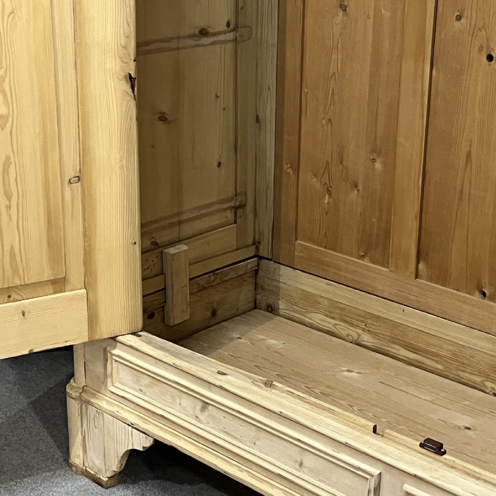 A large late nineteenth-century natural pine double wardrobe featuring a carved scroll pediment, arched door mouldings, and a flat plinth base. View VIII