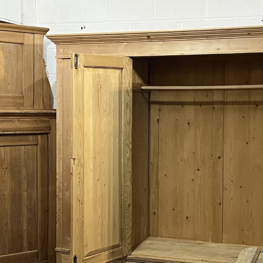 A large natural pine triple wardrobe featuring three vertical panelled doors above three aligned base drawers with turned wooden knobs. View III