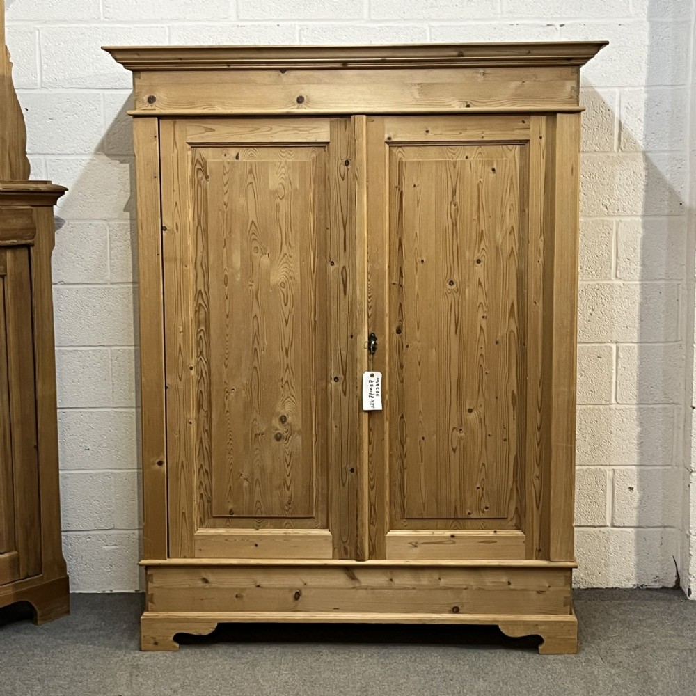A freestanding 1930s double pine wardrobe featuring twin recessed panel doors, a moulded top cornice, and a natural timber grain. View II