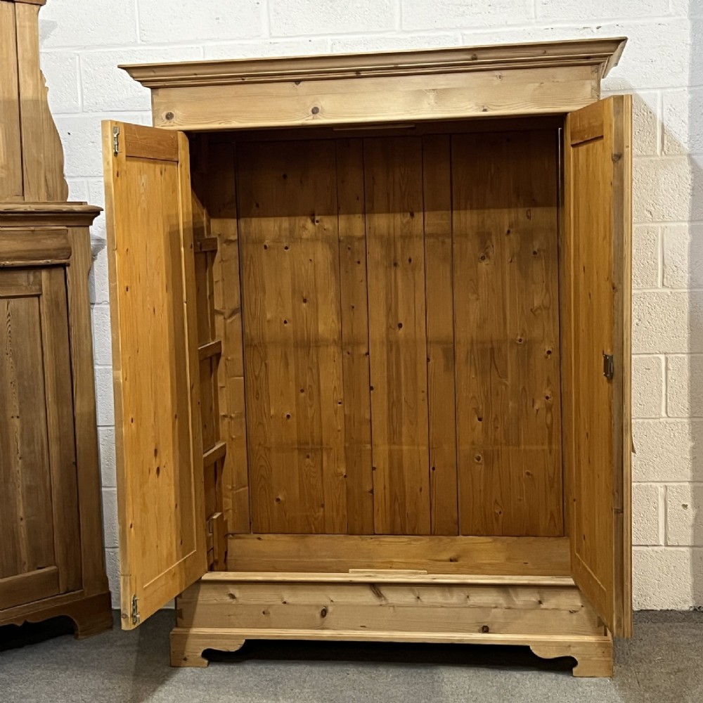 A freestanding 1930s double pine wardrobe featuring twin recessed panel doors, a moulded top cornice, and a natural timber grain. View III