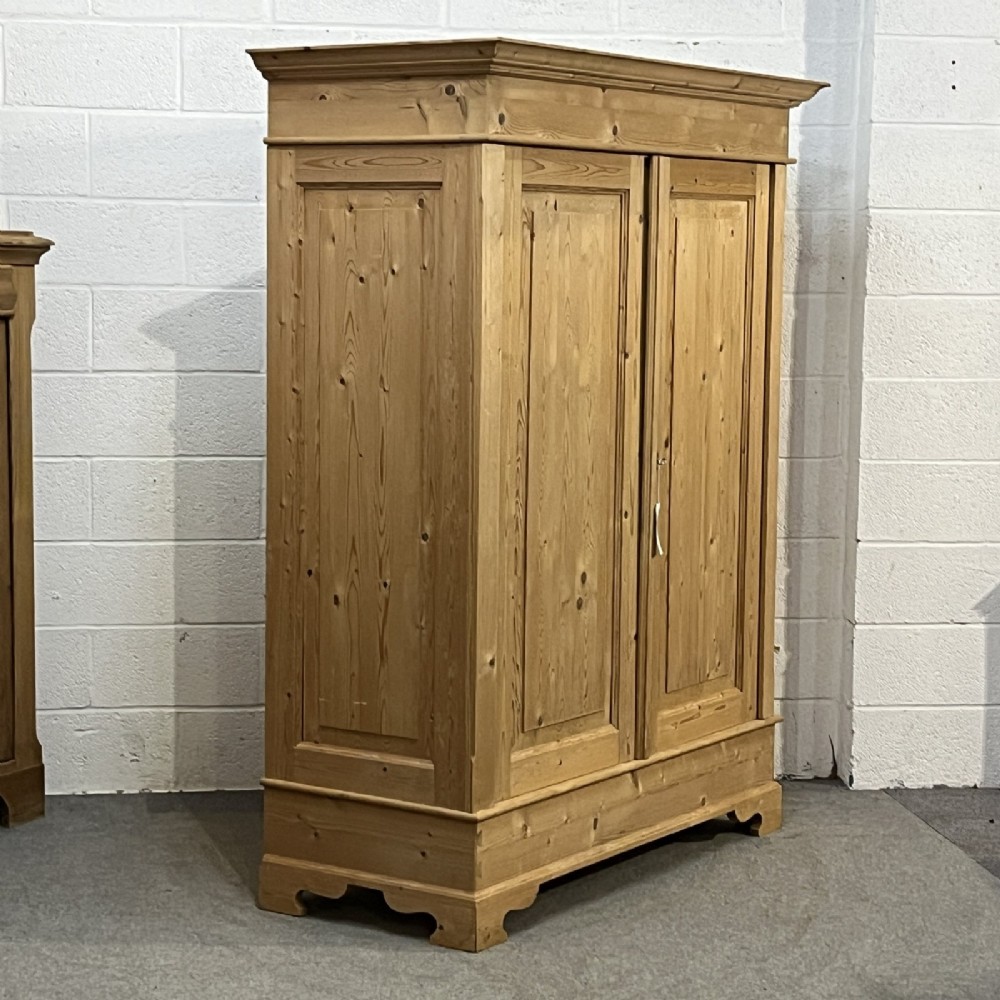 A freestanding 1930s double pine wardrobe featuring twin recessed panel doors, a moulded top cornice, and a natural timber grain. View V