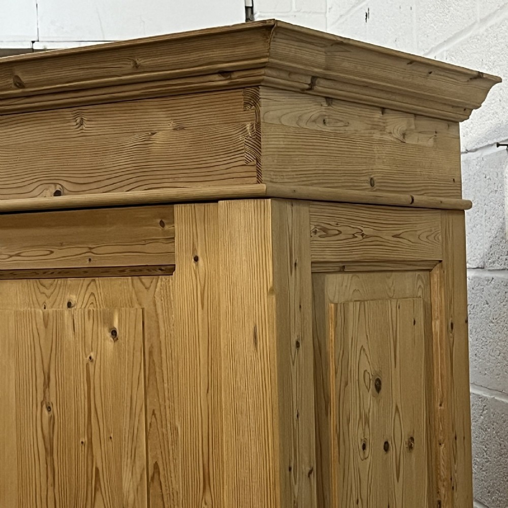 A freestanding 1930s double pine wardrobe featuring twin recessed panel doors, a moulded top cornice, and a natural timber grain. View VI