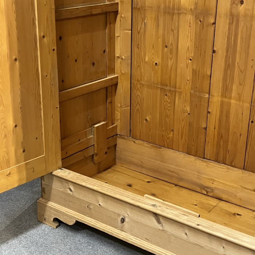 A freestanding 1930s double pine wardrobe featuring twin recessed panel doors, a moulded top cornice, and a natural timber grain. View VIII