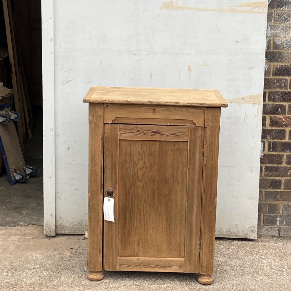 An antique natural pine church lectern cupboard featuring a hinged sloped top, single panelled door, and turned bun feet. View II