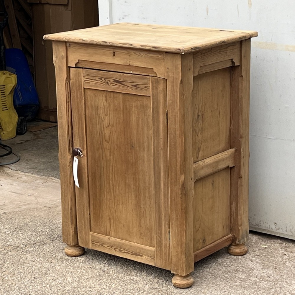 An antique natural pine church lectern cupboard featuring a hinged sloped top, single panelled door, and turned bun feet. View III