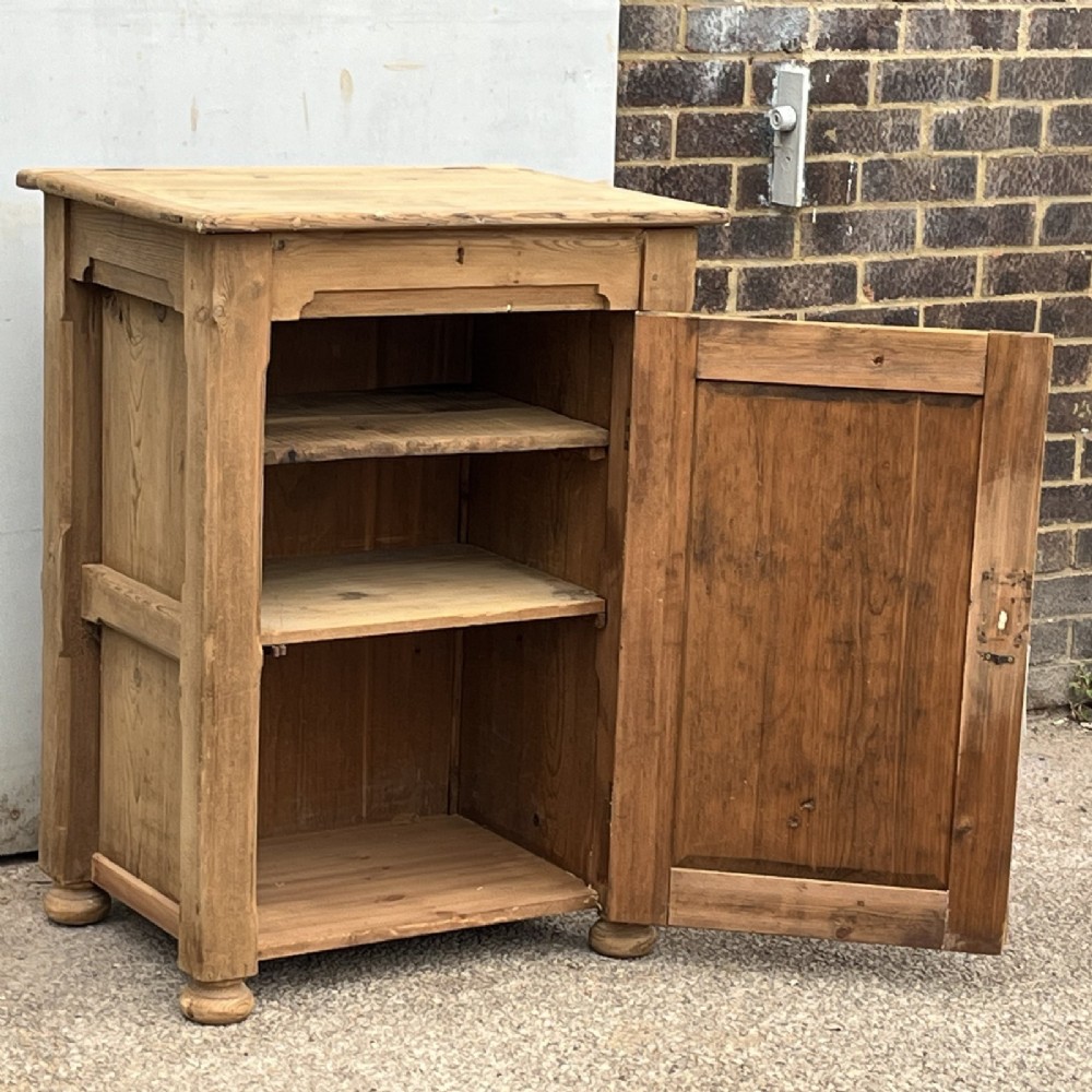 An antique natural pine church lectern cupboard featuring a hinged sloped top, single panelled door, and turned bun feet. View V