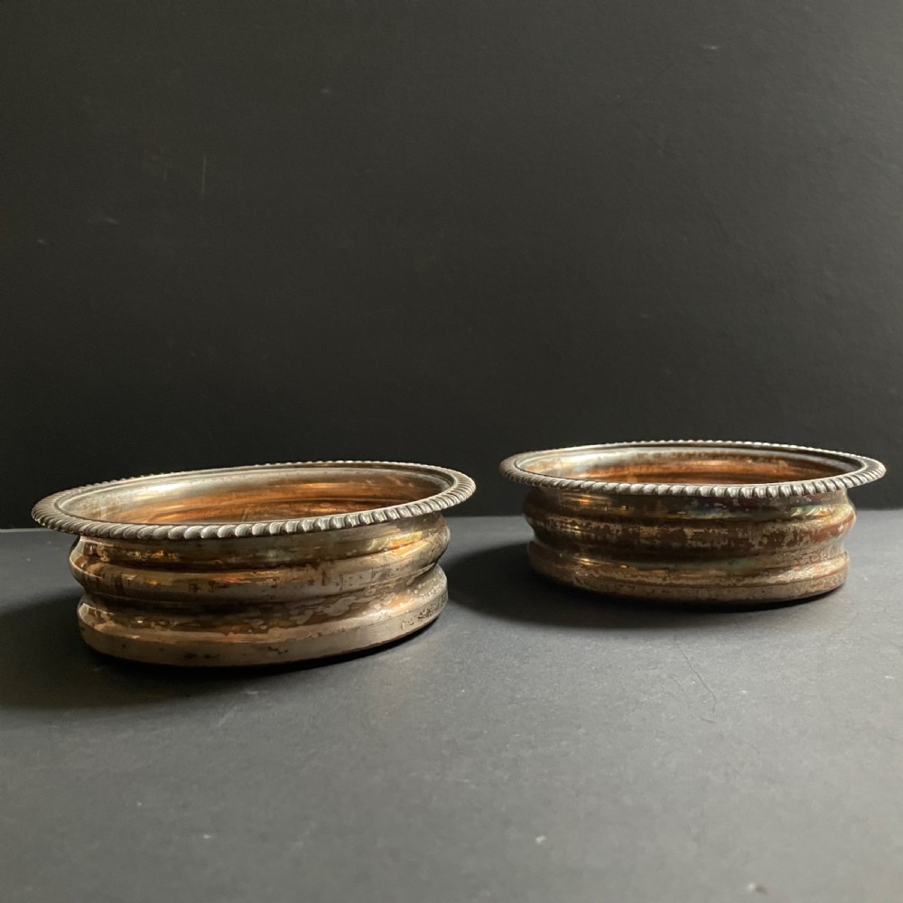 A pair of antique Georgian Old Sheffield Plate wine coasters featuring gadrooned rims and turned wooden bases. View II