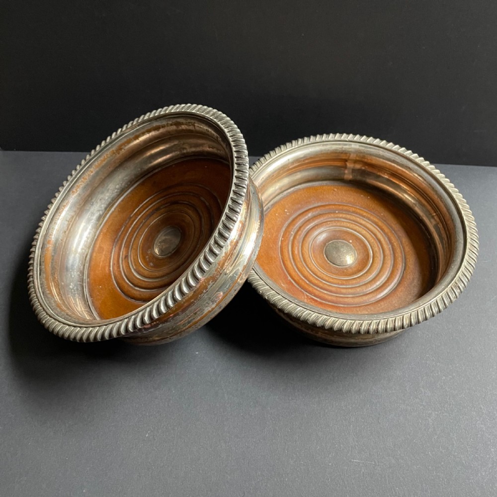 A pair of antique Georgian Old Sheffield Plate wine coasters featuring gadrooned rims and turned wooden bases. View III