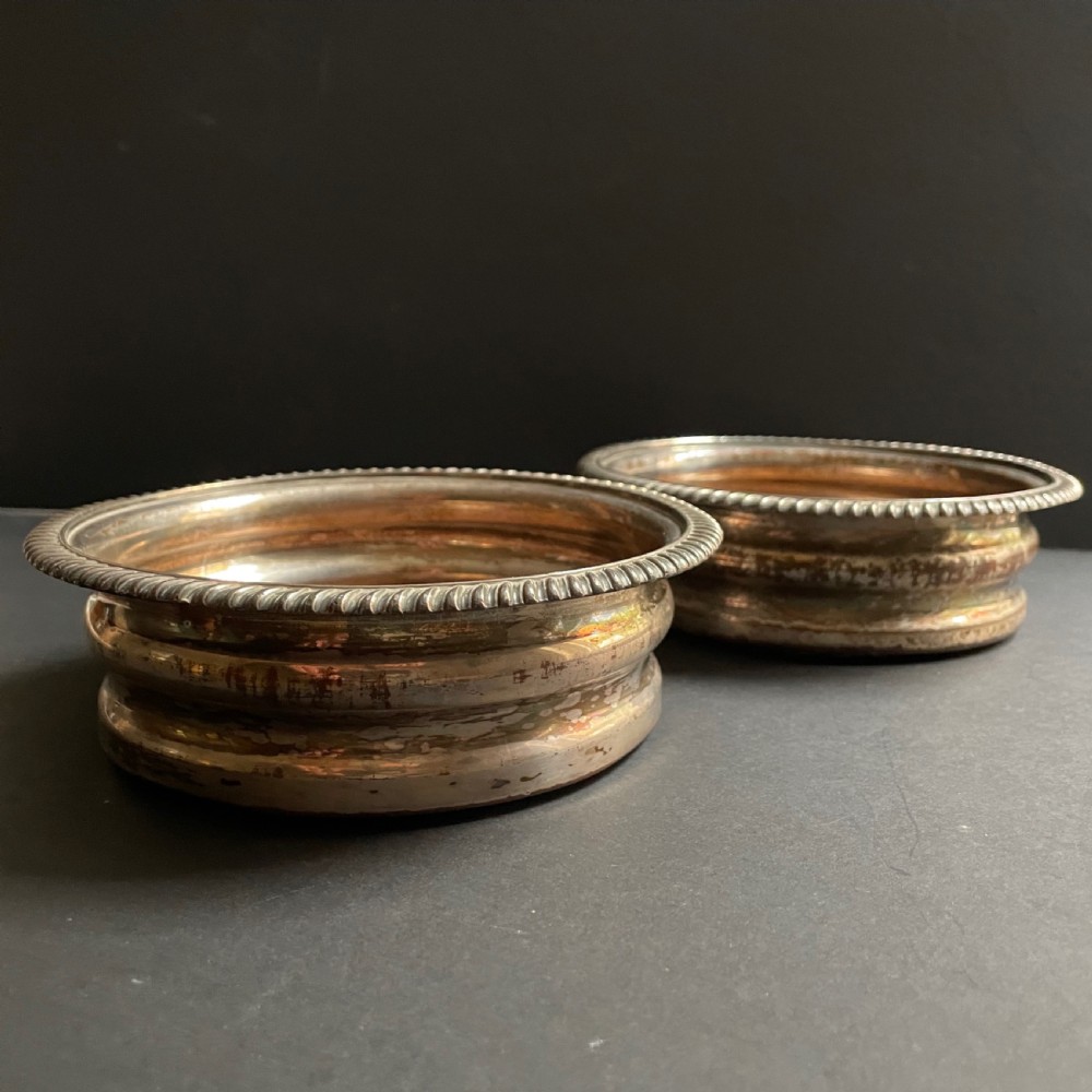 A pair of antique Georgian Old Sheffield Plate wine coasters featuring gadrooned rims and turned wooden bases. View VII