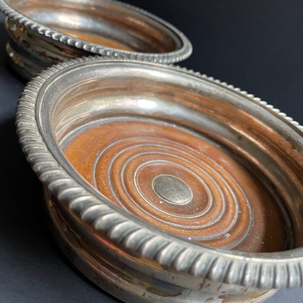 A pair of antique Georgian Old Sheffield Plate wine coasters featuring gadrooned rims and turned wooden bases. View VIII