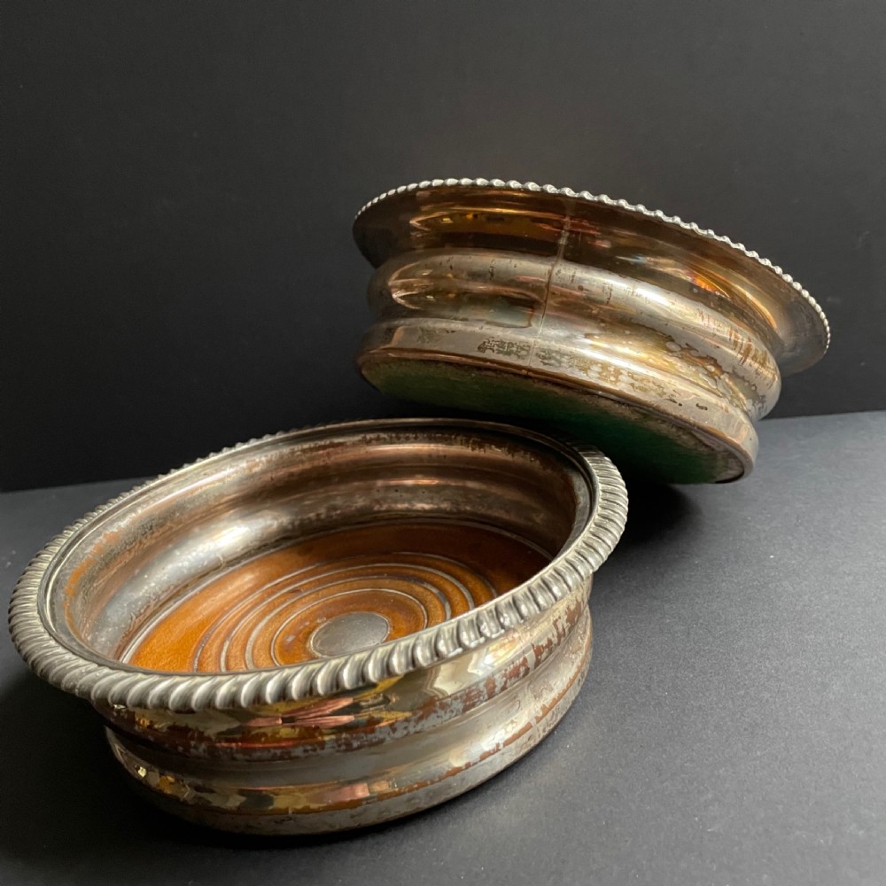 A pair of antique Georgian Old Sheffield Plate wine coasters featuring gadrooned rims and turned wooden bases. View IX
