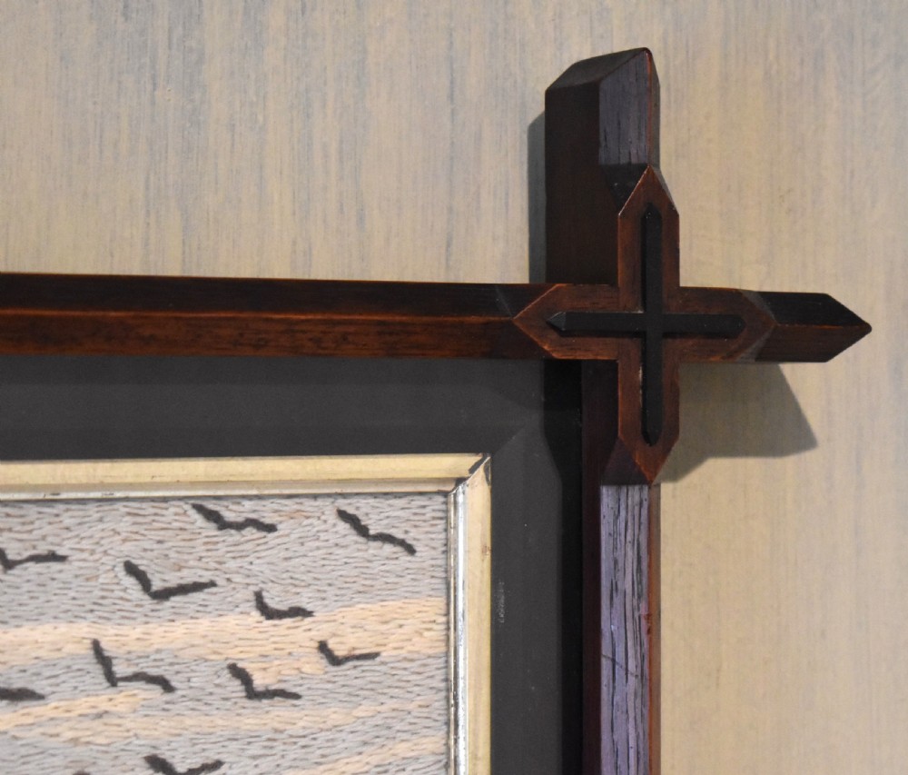 An Arts and Crafts needlework picture depicting a thatched cottage landscape framed in a dark stained wood frame with crossed corner joints. View V