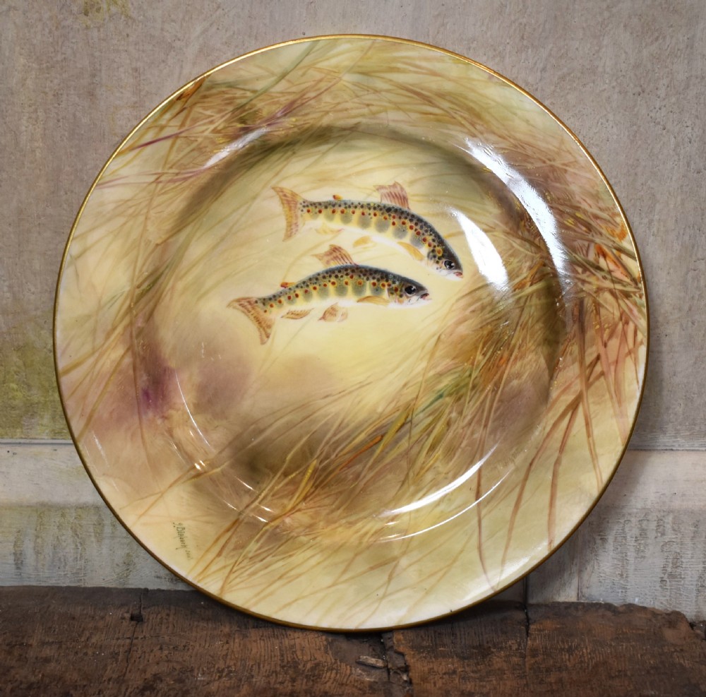 A circular porcelain cabinet plate with hand-painted trout amongst reeds and a gold gilded edge.