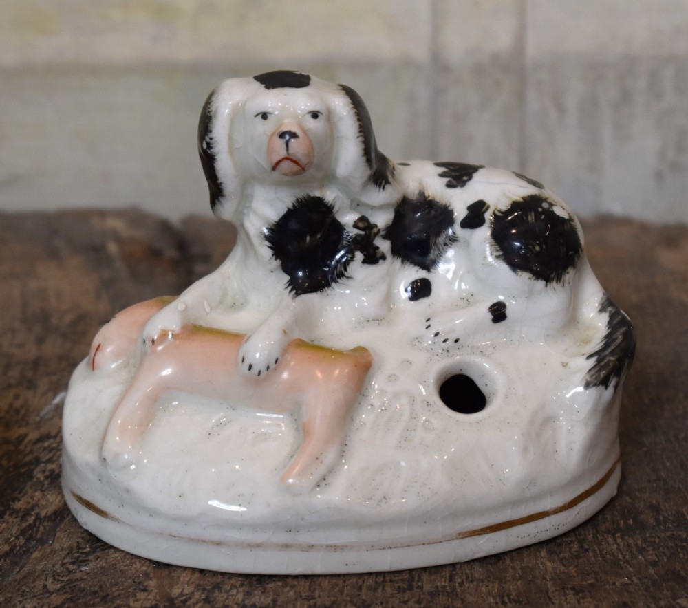 A pair of antique Staffordshire earthenware quill holders depicting black and white reclining spaniels with game at their paws on oval bases. View III