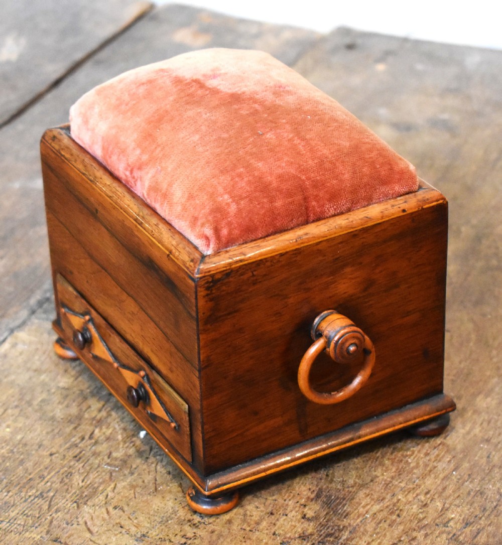 A small rectangular rosewood workbox featuring a terracotta velvet pincushion top, side handles, turned feet, and a drawer with inlaid diamond motifs. View II
