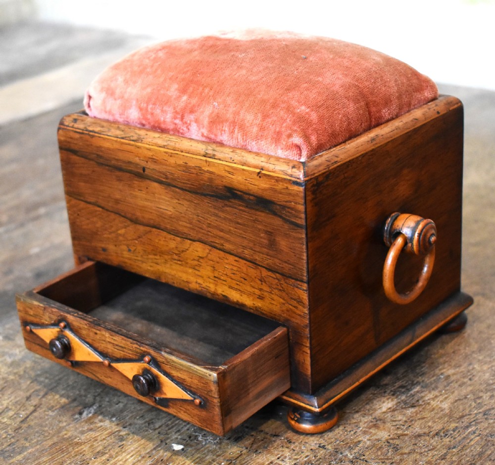 A small rectangular rosewood workbox featuring a terracotta velvet pincushion top, side handles, turned feet, and a drawer with inlaid diamond motifs. View III