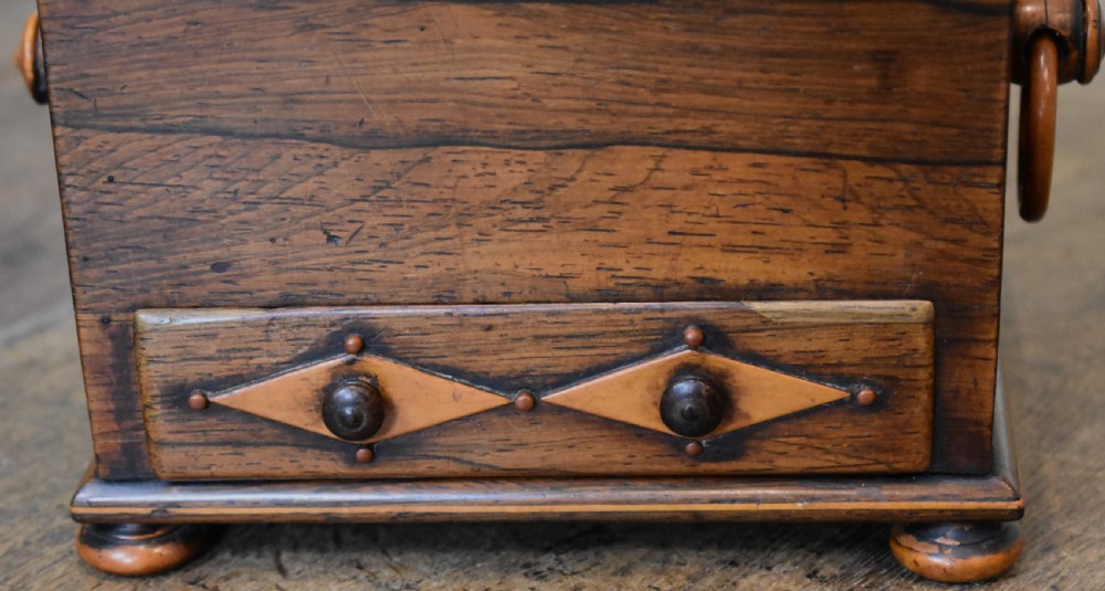 A small rectangular rosewood workbox featuring a terracotta velvet pincushion top, side handles, turned feet, and a drawer with inlaid diamond motifs. View IV