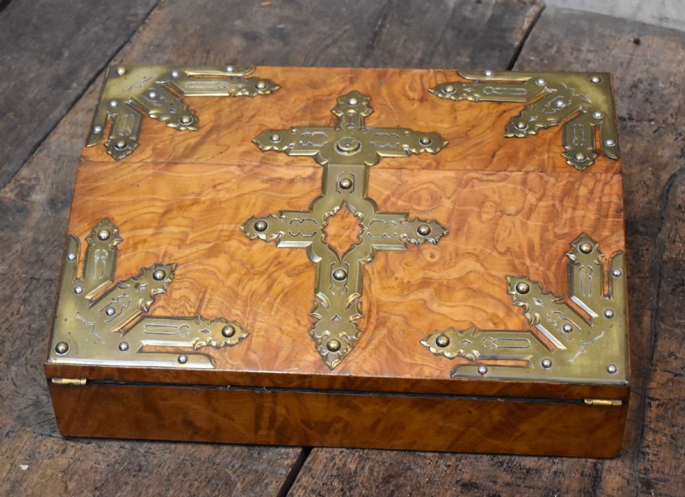 A closed rectangular wooden writing slope crafted from highly figured ash timber with ornate brass straps and corner mounts.