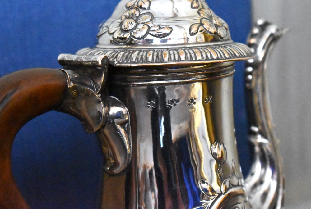 An antique Georgian silver-plated coffee pot featuring repousse floral scrollwork, an engraved cartouche, a carved wooden handle, and a finial lid. View IV