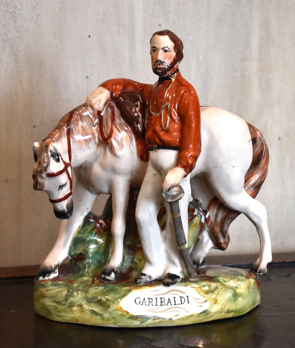 Victorian Staffordshire pottery figure representing Giuseppe Garibaldi standing beside a horse on a moulded ceramic base.