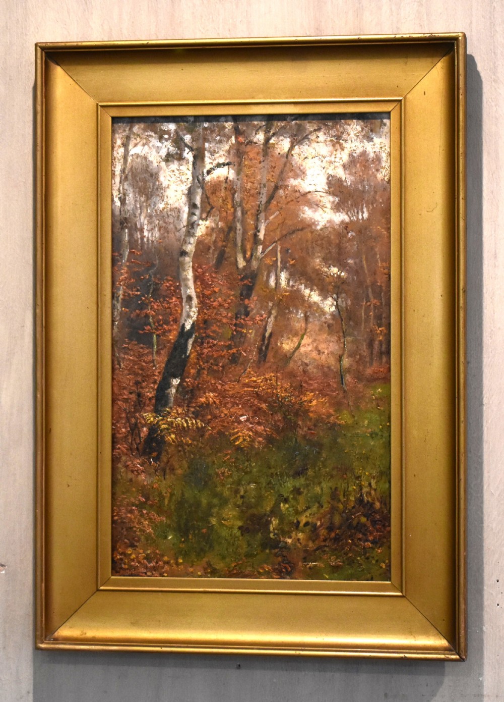 An oil painting depicting an autumnal woodland with birch trees and foliage, set within a wide bevelled gilded frame. View VI