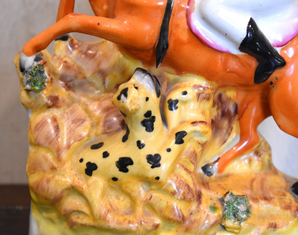 A Victorian Staffordshire earthenware figure depicting an equestrian hunter with a spear riding an orange horse over a spotted leopard on a moulded base. View II