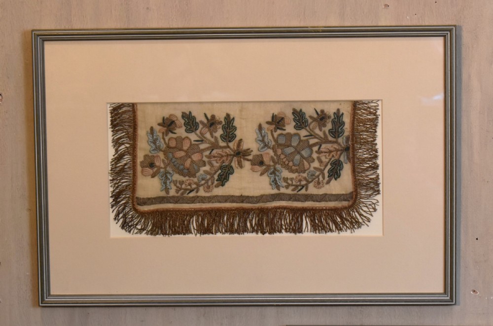 Set of three framed antique needlework panels displaying intricate botanical embroidery, mounted in cream pass-partout and light grey frames. View II