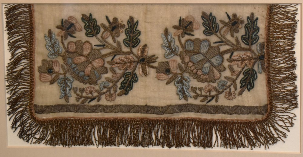 Set of three framed antique needlework panels displaying intricate botanical embroidery, mounted in cream pass-partout and light grey frames. View III