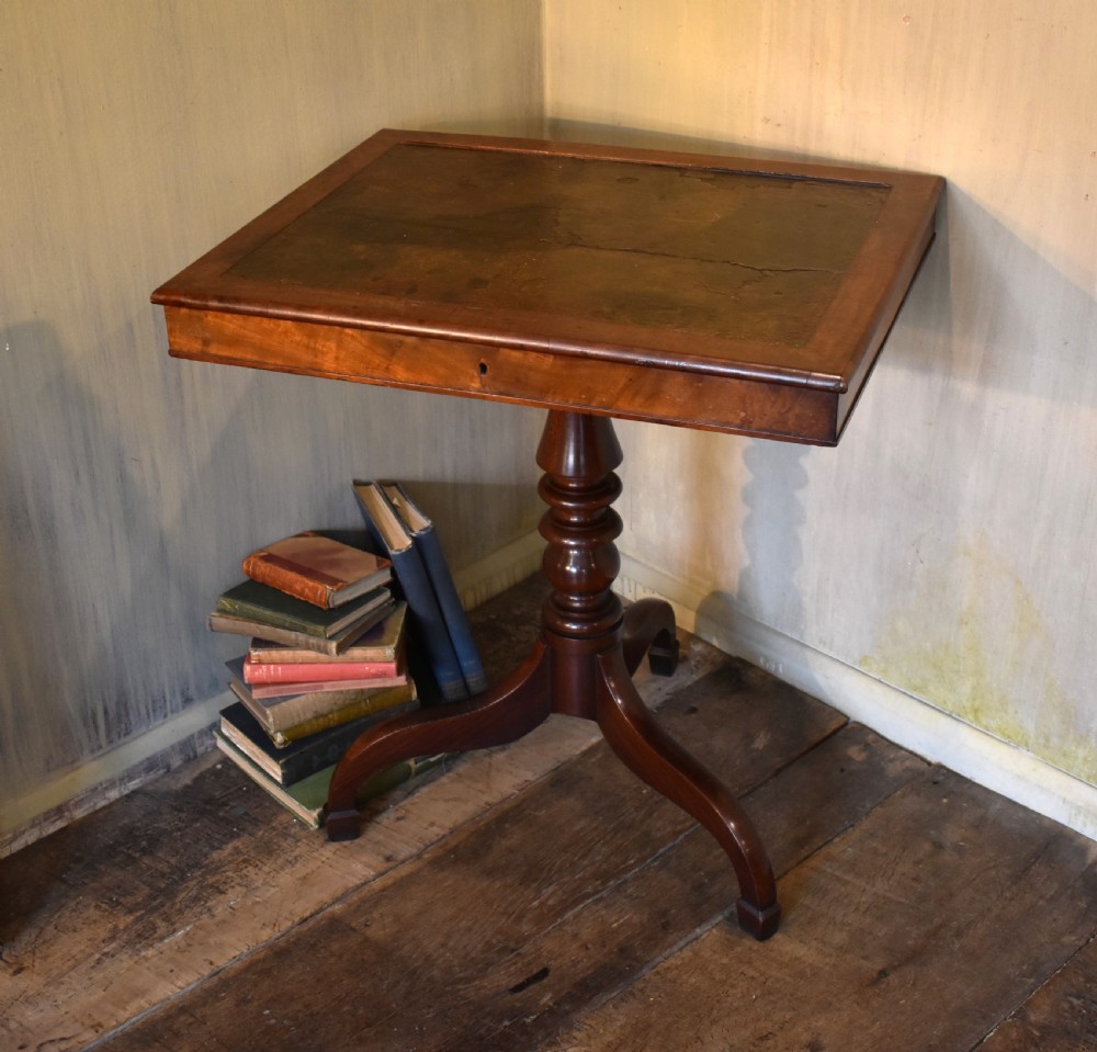 A Georgian mahogany library table featuring a rectangular leather-inset top supported by a turned pedestal stem and tripod swept legs.